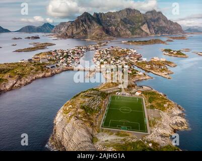 Unglaubliche Luftaufnahme von henningsvær, seine malerische Fußballplatz und die Berge im Hintergrund. Ein kleines Fischerdorf auf mehrere kleine ist Stockfoto