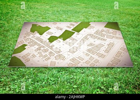 Karton auf dem Boden mit einem immaginary Stadtplan über ein grünes Gras gelegt - freie Grundstücke zum Verkauf Konzept Bild. Stockfoto