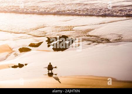 Blick von oben auf ein Surfer am Strand zu sitzen Stockfoto