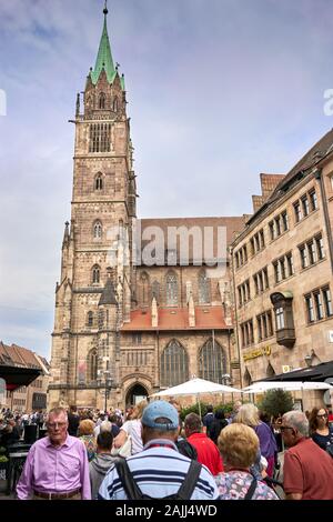 Die berühmte 700 Jahre alte St. Laurentius-Kirche in Nürnberg, Deutschland, mit der engen Straße, die im Sommer von Touristen und Käufern überfüllt ist. Stockfoto