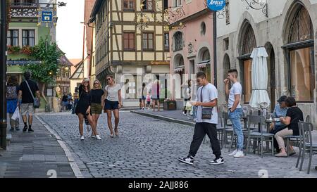 Straßenszene im mittelalterlichen Dorf mit Touristen, die Selfies machen und das schöne Sommerwetter in dieser großen Touristenstadt Rothenburg genießen. Stockfoto