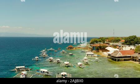 Menschen Schnorcheln über Korallenriff mit klaren, blauen Wasser des Ozeans, Ansicht von oben. Moalboal, Philippinen. Menschen schwimmen im transparenten Meer zwischen Korallenriffen. Sommer und Reisen Urlaub Konzept. Stockfoto