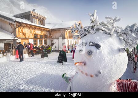 Schneemann auf der sonnigen Terrasse des schneebedeckten Hochfeldernalm-Hüttenrestaurants Grußspieße im Skigebiet Ehrwalder Alm, Österreich, Tyrol Stockfoto