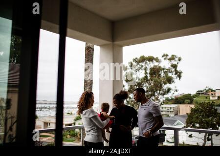 Gemischte Familie steht auf Balkon mit Blick auf das Meer Stockfoto