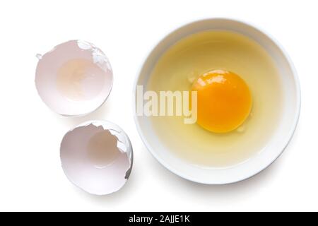 Gebrochen weißer Keramik Ei in einer Schüssel neben einer Eierschale isoliert auf Weiss. Ansicht von oben. Stockfoto