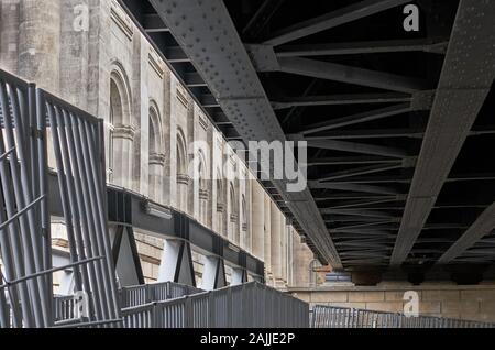 Interessante architektonische Strukturen mit konvergierenden Linien von Stahl und Stein, von der Unterseite eines erhöhten Urban train trestle in Berlin, Deutschland. Stockfoto