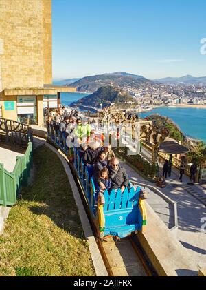 Touristen auf die Achterbahn des Monte Igueldo Vergnügungspark mit der Concha Bucht von San Sebastian im Hintergrund, Baskenland, Spanien. Stockfoto