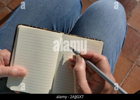 Eine Frau mit einem leeren Notizbuch, Stift in der Hand Stockfoto