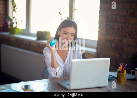 Nette junge Frau mit einem kleinen blauen Masseur Stockfoto