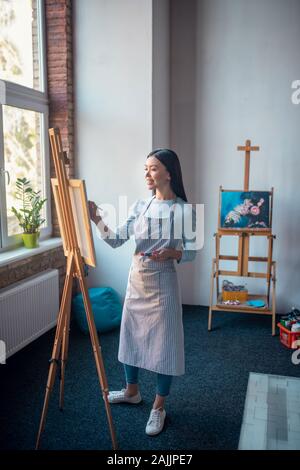 Glückliche junge Frau mit Schürze im Studio Stockfoto