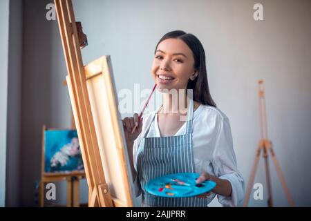 Frohe glückliche Frau halten Sie die Bürste in die Hand Stockfoto