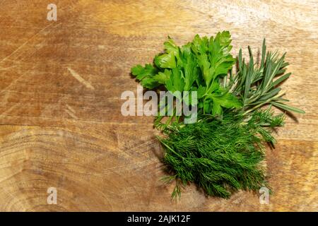 Frische Gewürze. Dill, Rosmarin und Petersilie in einer ländlichen Umgebung auf einem hölzernen Hintergrund Stockfoto