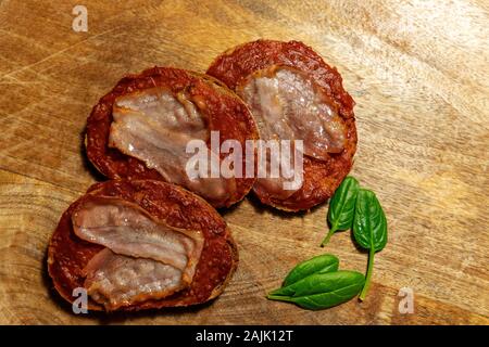 Geschnittenes Brot mit Tomatenmark und Speck auf einer hölzernen Hintergrund Stockfoto