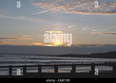 Sonnenuntergang auf Littlehampton Küste wie die Sonne taucht hinter Wolke am Horizont, die schönen Farben auf den Wolken. Stockfoto