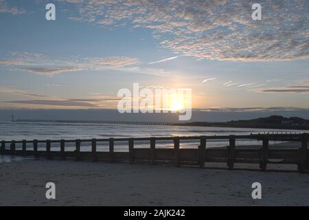 Schönen Sonnenuntergang auf Littlehampton Küste wie die Sonne taucht hinter Wolke am Horizont, die lebhaften Farben auf den Wolken. Stockfoto