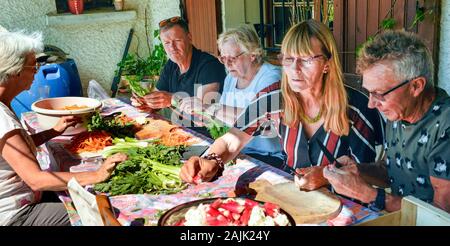 Familie Mitglieder vorbereiten Salate zum Feiern. Provence Frankreich August Stockfoto