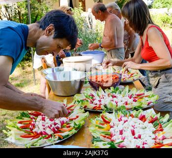 Familie Mitglieder vorbereiten Salate zum Feiern. Provence Frankreich August Stockfoto