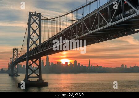 Sonnenuntergang über dem westlichen Spannweite der Bay Bridge und San Franciscos Hafengebiet. Stockfoto