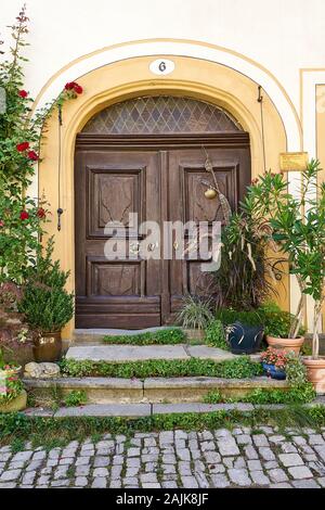 Mittelalterlichen Hauseingang mit schöner Holztür und abgenutzten Steinplatten am Eingang, an der Kopfsteinpflasterstraße. Stockfoto