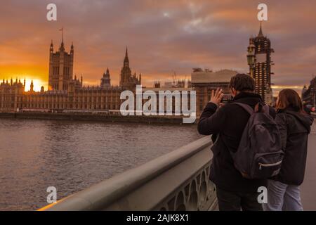 Westminster, London, 4. Jan 2020. Ein Mann einrastet und den Sonnenuntergang. Touristen und Einheimische, die das Londoner genießen Sie den schönen Sonnenuntergang auf die Westminster Bridge mit dem Parlament in den Hintergrund. Ruhe und trockenen Bedingungen in London am Ende einer wunderschön sonnigen Tag in der Hauptstadt. Stockfoto