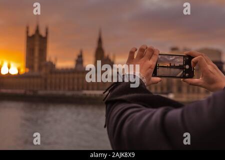 Westminster, London, 4. Jan 2020. Ein Mann einrastet und den Sonnenuntergang. Touristen und Einheimische, die das Londoner genießen Sie den schönen Sonnenuntergang auf die Westminster Bridge mit dem Parlament in den Hintergrund. Ruhe und trockenen Bedingungen in London am Ende einer wunderschön sonnigen Tag in der Hauptstadt. Stockfoto