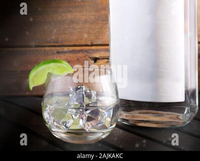 Gin Flasche und Glas mit Eis und einem grünen Kalk Stockfoto