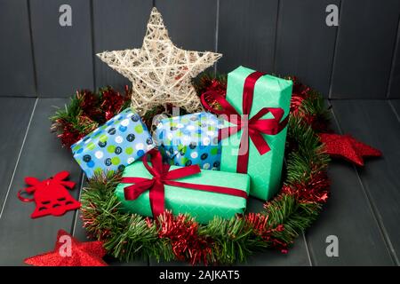 Weihnachten Geschenke verpackt und mit Geschenkpapier und Tuch Krawatten, grüne und rote Lametta und Gold Star auf dunklem Hintergrund Stockfoto