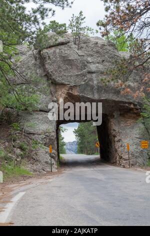 Die einspurige Scovel Johnson Tunnel auf Iron Mountain Road mit Vorsicht Zeichen und einen Blick auf den Mount Rushmore im Hintergrund. Stockfoto