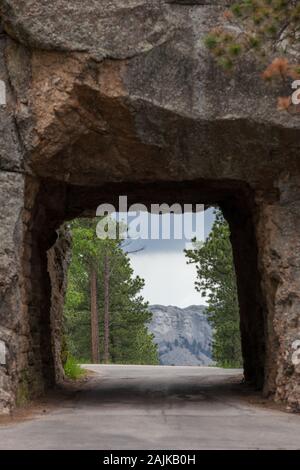 Die einspurige Scovel Johnson Tunnel auf Iron Mountain Road mit Vorsicht Zeichen und einen Blick auf den Mount Rushmore im Hintergrund. Stockfoto