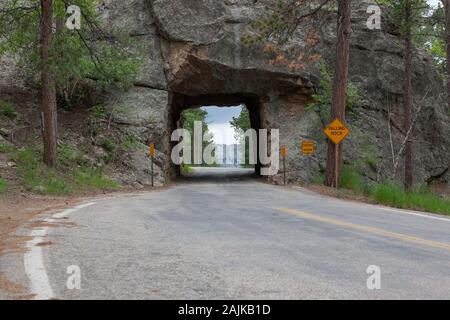 Die einspurige Scovel Johnson Tunnel auf Iron Mountain Road mit Vorsicht Zeichen und einen Blick auf den Mount Rushmore im Hintergrund. Stockfoto