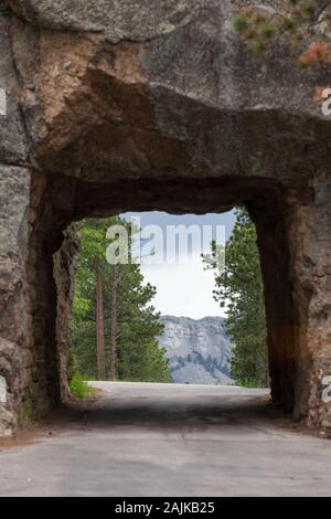 Die einspurige Scovel Johnson Tunnel auf Iron Mountain Road mit Vorsicht Zeichen und einen Blick auf den Mount Rushmore im Hintergrund. Stockfoto