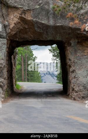 Die einspurige Scovel Johnson Tunnel auf Iron Mountain Road mit Vorsicht Zeichen und einen Blick auf den Mount Rushmore im Hintergrund. Stockfoto