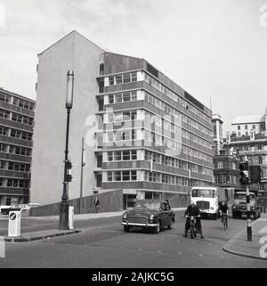 1960er Jahre, historisch, London, großer moderner Büroblock, City of London mit Kraftfahrzeugen der Epoche in einer Straße, darunter ein Auto, ein LKW und ein Motorrad. Stockfoto