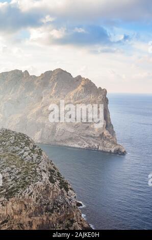 Sicht auf die Klippen von Mirador Es Colomer in Cap de Formentor, Mallorca, Balearen, Spanien. Felsen im Mittelmeer vom Meer umgeben ist. Sonnenstrahlen scheint auf den Klippen. Wolken im Himmel. Vertikale Foto. Stockfoto