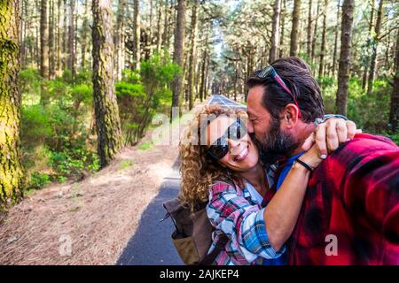 Glückliche Menschen kaukasischen Paar genießt die Outdoor Freizeitaktivitäten Aktivität zusammen in einem Wald unterwegs auf eine lange Asphaltstraße - alternative kaukasischen Mann Stockfoto