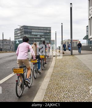 Eine Gruppe junger Erwachsener nimmt eine Fahrradtour durch die Straßen von Berlin mit einer einzigen Datei auf der Fahrradspur in der Nähe des Hauptbahnhofs vor. Stockfoto