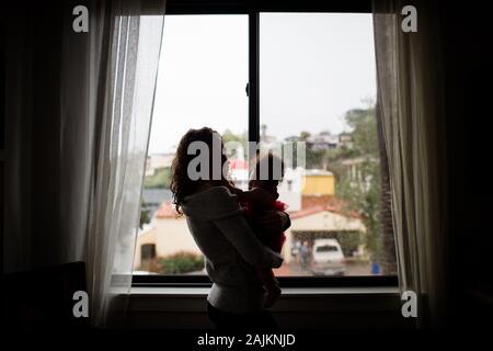 Ende dreißiger Jahre Mutter, die Baby vor dem Fenster für Silouette hält Stockfoto