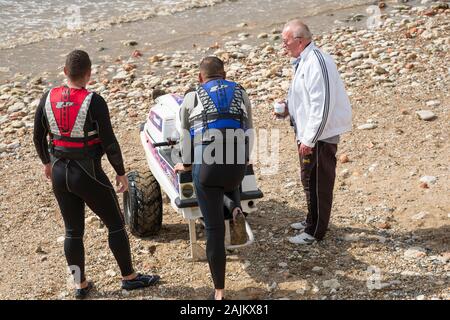 Drei stehende Männer um ein Jet Ski auf einem Kieselstrand Stockfoto