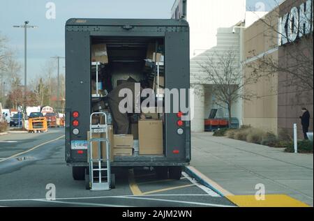 Berlin, CT/USA - November 25, 2019: UPS LKW außerhalb eines Kohl Geschäft geparkt, Ein Anlieferung Treiber Sortieren durch die Pakete in der Rückseite Stockfoto