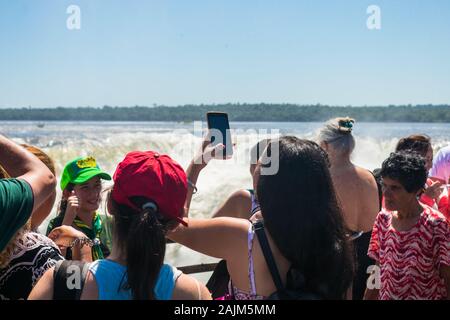 Frau Aufnehmen von Fotos mit Ihrem Smartphone in der Nähe der Kehle des Teufels, der größte Kaskade aus der Iguazu Wasserfälle Stockfoto