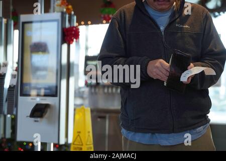 Cromwell, CT/USA - November 25, 2019: Asiatischer mann Sortieren durch Geld in der Brieftasche nach Essen bestellen bei McDonalds Stockfoto