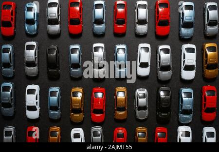 Blick von oben auf die geparkte Spielzeugautos auf einem schwarzen Hintergrund wie ein PKW-Parkplatz. Stockfoto