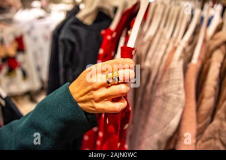 Moderne Frau einkaufen in Fashion Mall, die Wahl der neuen Kleidung, Kleiderbügel mit unterschiedlichen Casual bunten Kleider auf Kleiderbügeln
