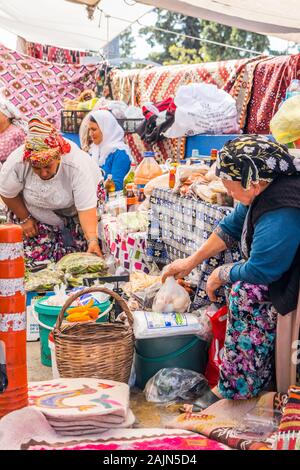 Bodrum, Türkei - 24 September 2019: Türkische Frauen verkaufen Teppiche und Souvenirs auf dem Markt. Der Markt findet wöchentlich statt Stockfoto