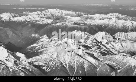 Eine schwarze und weiße Aussicht auf die schneebedeckten Rocky Mountains in British Columbia aus kommerzieller Ebene gesehen. Stockfoto