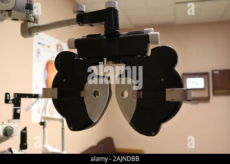 Patientenansicht hinter dem Phoropter im Untersuchungsraum des Auges sitzend, Sichtprüfung wird durchgeführt Stockfoto