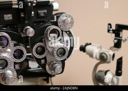 Nahaufnahme der Phoropter-Augen-Untersuchungsgeräte mit Schlitzlampe im Hintergrund Stockfoto