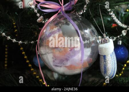 Little Baby Puppe in Crystal Ball mit bunten Bändern für Dekoration auf Winterurlaub oder Geschenk für Mädchen Stockfoto