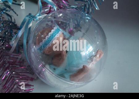 Little Baby Puppe in Crystal Ball mit bunten Bändern für Dekoration auf Winterurlaub oder Geschenk für Mädchen Stockfoto