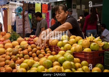 Oaxaca, Mexiko - 2019-11-30 - die Frau, die der Anbieter ordnet ihr die Frucht zum Verkauf. Stockfoto